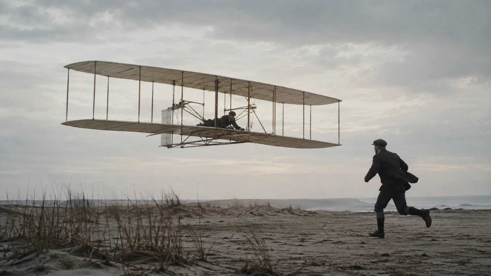The Wright Flyer lifting from the sand at Kill Devil Hills while one brother runs beside it